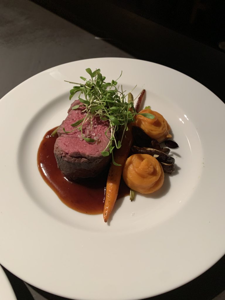 Rinderfilet mit Schwarzbiersoße, Karotten, Shitake & Kürbiskernen auf einem Teller