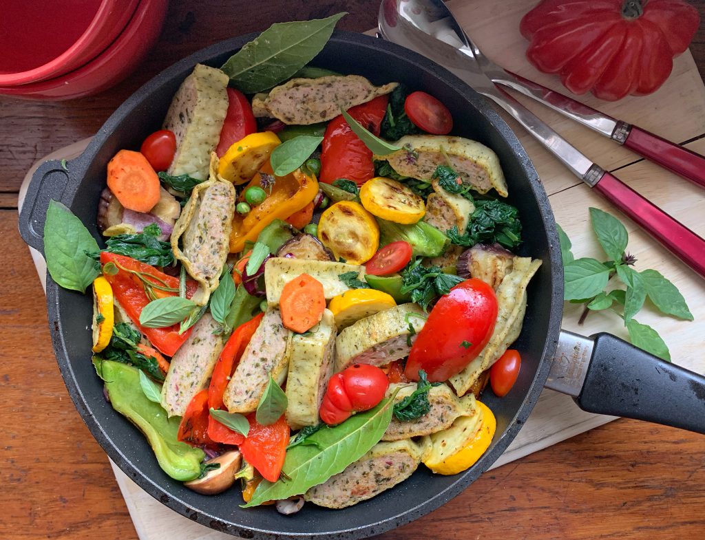 Bunte Maultaschenpfanne mit Gemüse und Bärlauch in einer Pfanne serviert. Daneben liegt Besteck.