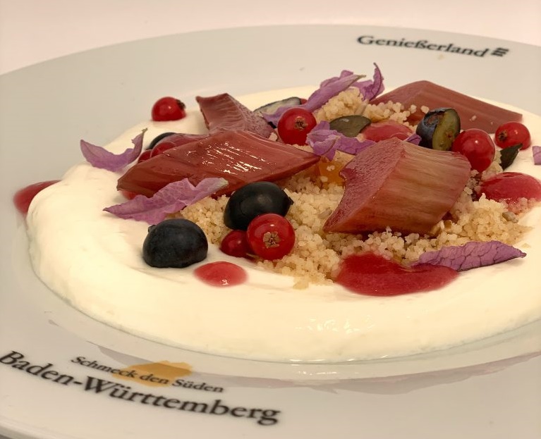 Süßer Couscous mit Rhabarber, Beeren und Joghurt auf einem Teller. 